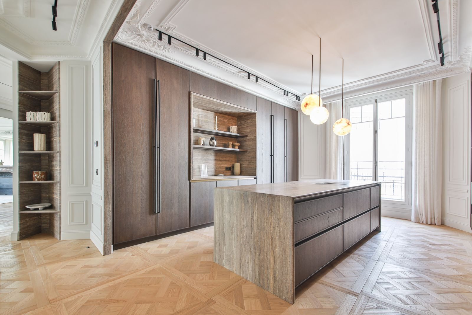 Kitchen of a renovated Haussmann apartment: travertine island, dark oak joinery, original ceiling mouldings