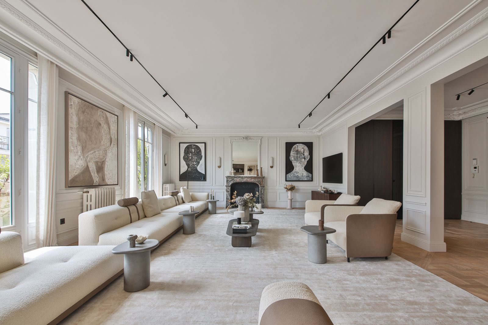 Reception room of a renovated Haussmann apartment in Paris: tall windows, mouldings, marble fireplace and oak parquet