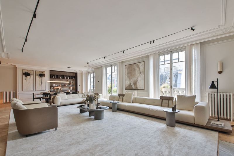 Salon with tall windows, cream sofas and panelled walls
